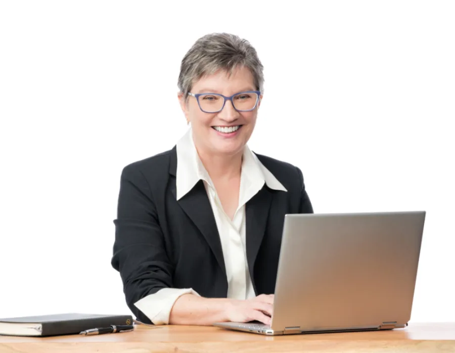 Kathy J. Lang seated at desk with laptop and notebook